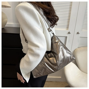 Detailed side view of a large silver metallic quilted tote bag worn by a model