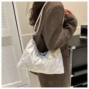 Detail of silver metallic quilted shoulder bag with white rope strap on a model