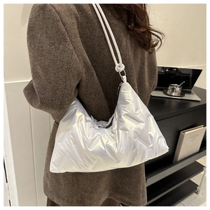 Detailed side view of white quilted shoulder bag with puffy padded texture and knotted strap