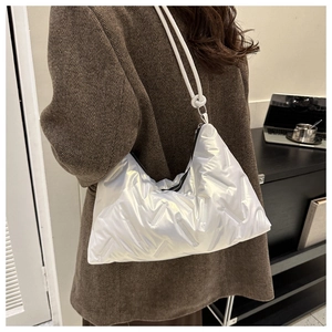 Detail of white quilted nylon shoulder bag showing puffy texture and sleek crescent shape