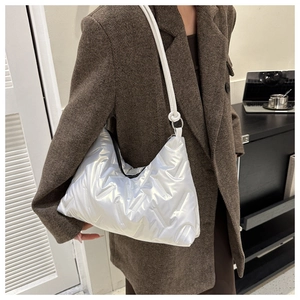 Detail of silver metallic quilted shoulder bag with puffer texture and zipper closure