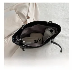 Vue de dessus d'un grand sac cabas noir contenant téléphone, portefeuille et parapluie