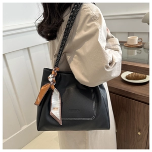 Détail d'un cabas noir en cuir grainé avec bandoulière tissée et foulard en soie décoratif