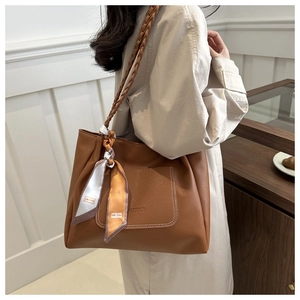 Brown litchi grain tote bag detail featuring woven strap and decorative silk scarf accessory