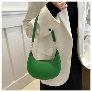 Sac hobo croissant vert avec boucles dorées porté sur un blazer blanc par un mannequin