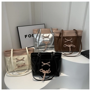 Détail de grands sacs fourre-tout en argent, marron, crème et noir avec cordons à nœuds décoratifs