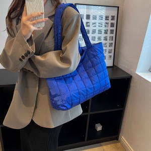 Royal blue quilted puffer tote bag shown on model with chic oversized khaki blazer