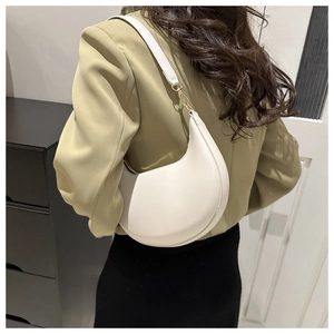 Side view of white crescent shoulder bag with gold hardware on female model