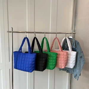 Quilted down nylon tote bags in assorted colors hanging on a minimalist display