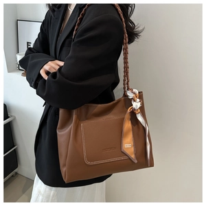 Detail of soft leather brown tote bag with woven shoulder straps and floral silk scarf decor