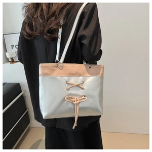 Détail du cabas en cuir beige et argent métallisé avec laçage décoratif et nœud élégant