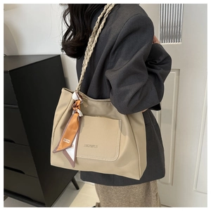 Detail of beige lychee leather tote bag with woven strap and decorative silk scarf