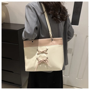 Détail du sac cabas bicolore avec laçage croisé décoratif et œillets métalliques élégants