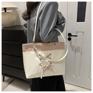 Détail du sac cabas bicolore avec ruban noué et finition en cuir mat élégant