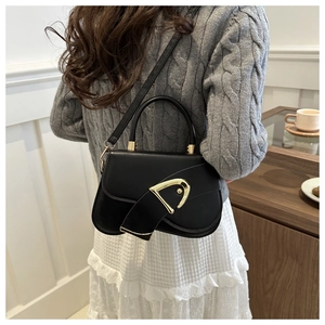 Detail of black saddle bag featuring golden D-shaped metal buckle and leather texture