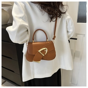 Brown leather handbag with gold D-buckle shown on model in white blazer and black skirt
