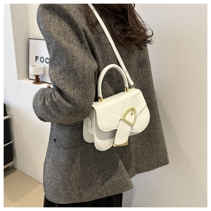 Minimalist white square bag with golden buckle shown on a model in a blazer