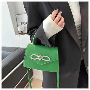 Detail van groene leren handtas met glanzende strass-strik en envelopsluiting