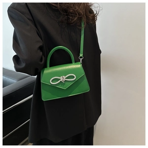 Detail van groene lederen mini tas met zilveren strass strik en handvat