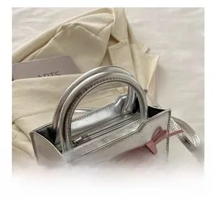 Detail showing the silver metallic handbag with a pink bow and a detachable shoulder strap