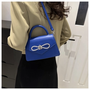 Detail van de modieuze koningsblauwe crossbodytas met een sprankelende stras-strikdecor
