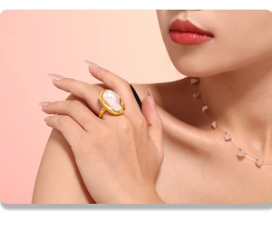 Detail of baroque pearl ring with hammered gold texture on a model's finger