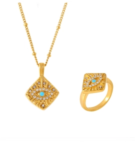 Macro detail of gold-plated evil eye pendant and ring set with turquoise and zircons
