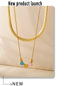 Détail d'un collier double épaisseur doré avec breloques cœur colorées sur soie