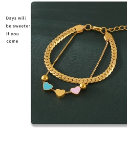 Détail d'un bracelet double couche doré avec des breloques cœurs sur cuir vert foncé