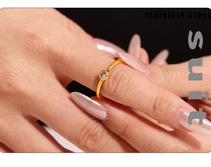 Gros plan d'une bague en acier inoxydable doré avec un diamant rond serti clos sur une main