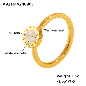 Détail macro d'une bague dorée en titane avec nacre blanche et chiffres romains gravés