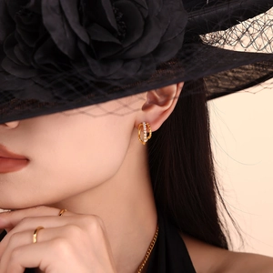 Eleganti orecchini di perle dorate su modella con cappello nero e anelli dorati