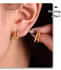 Effet porté de boucles d'oreilles dorées en forme de U avec cristaux blancs sertis