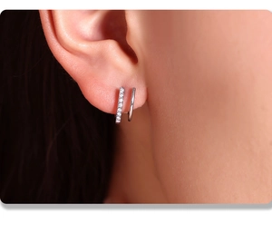 Gros plan de boucles d'oreilles double couche en argent avec pavage de zircone sur l'oreille
