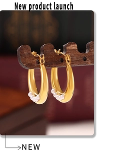 Gros plan de boucles d'oreilles en U dorées 18K avec perles sur support en bois brun