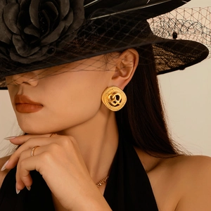 Vintage gouden hartvormige oorbellen op een model met een elegante zwarte hoed