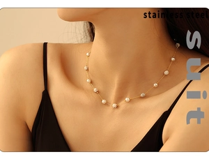 Detail of stainless steel necklace with white pearls and geometric beads on a model