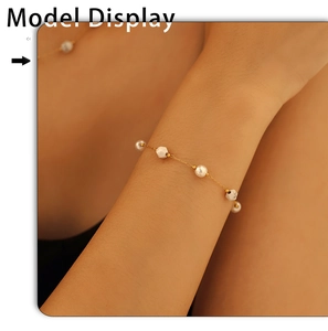 Detail of elegant gold chain bracelet with white pearls and hexagonal beads on model