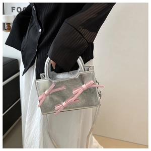 Detail of silver metallic handbag featuring three pink 3D bows and a slim shoulder strap