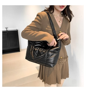 Detail of a black quilted puffer tote bag shown on model in a minimalist setting