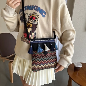 Close-up of bohemian crossbody bag with colorful woven patterns and blue tassels