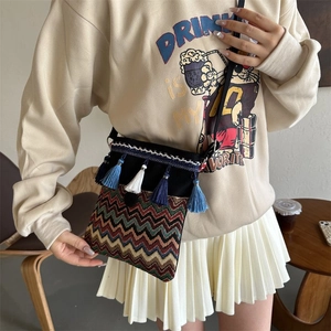 Detail of bohemian crossbody bag with colorful woven patterns and vibrant blue tassels