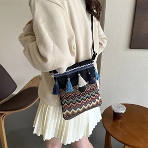 Detailed view of bohemian crossbody bag with colorful weave patterns and blue tassels