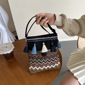 Close-up of ethnic crossbody bag with bohemian embroidery, colorful tassels and canvas