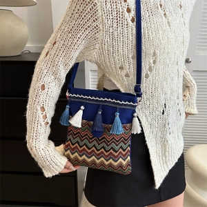 Close-up of colorful wave embroidery and blue tassels on an ethnic crossbody bag