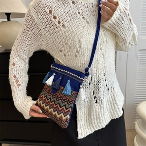 Detailed view of bohemian crossbody bag with colorful weave pattern and blue tassels