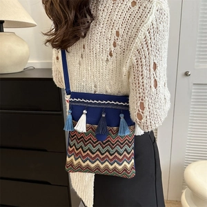 Detail of ethnic crossbody bag with blue tassels and colorful zigzag embroidery texture