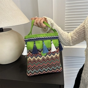 Detailed shot of green canvas ethnic bag with colorful woven patterns and tassel accents