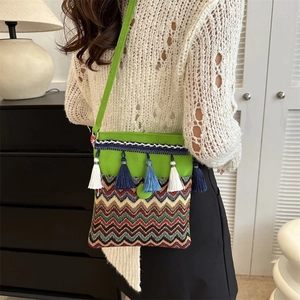 Detail of green ethnic crossbody bag featuring colorful embroidery and long tassels decoration
