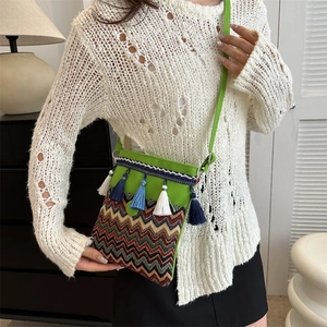 Macro detail of bohemian crossbody bag with colorful tassels and ethnic embroidery texture